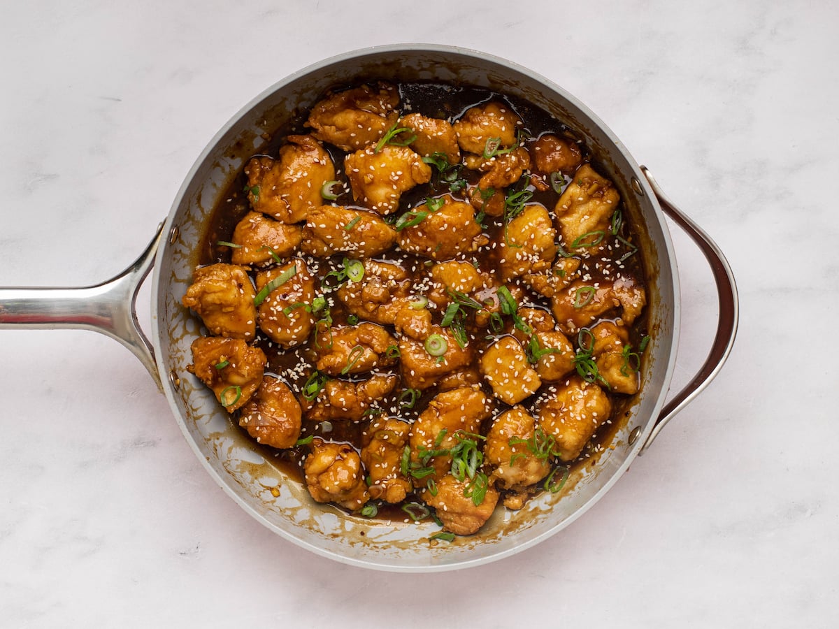 general tso's chicken in skillet with scallions and sesame seeds