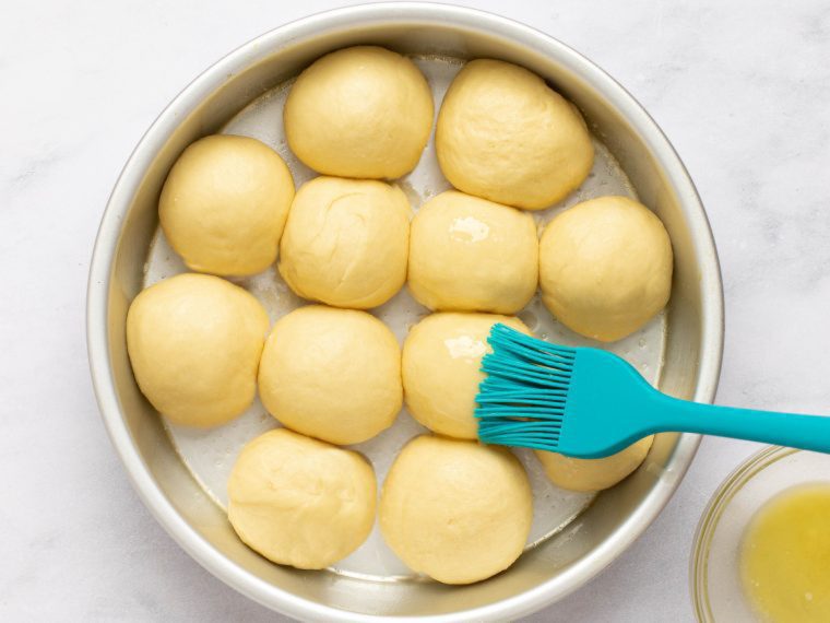 brushing dinner rolls with melted butter before baking