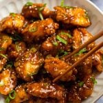 Chopsticks grabbing a piece of General Tso's chicken.