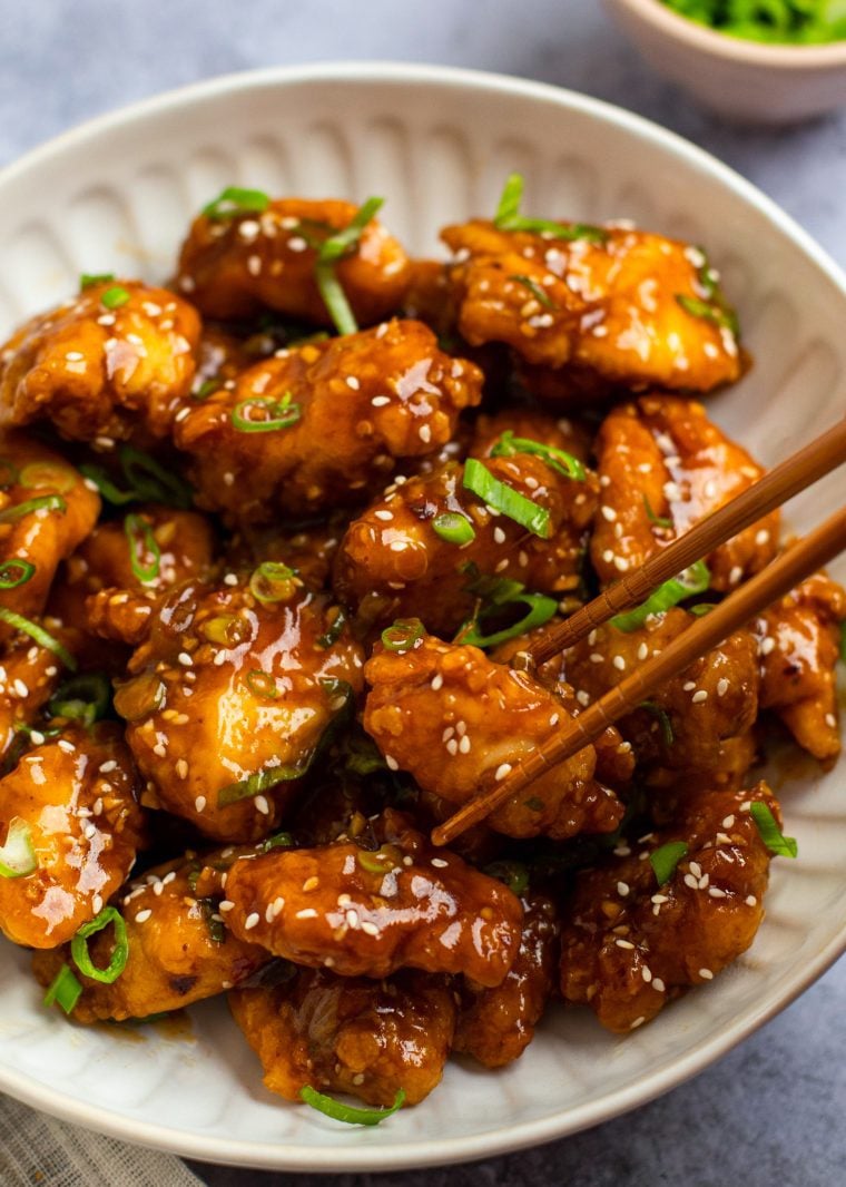 Chopsticks grabbing a piece of General Tso's chicken.