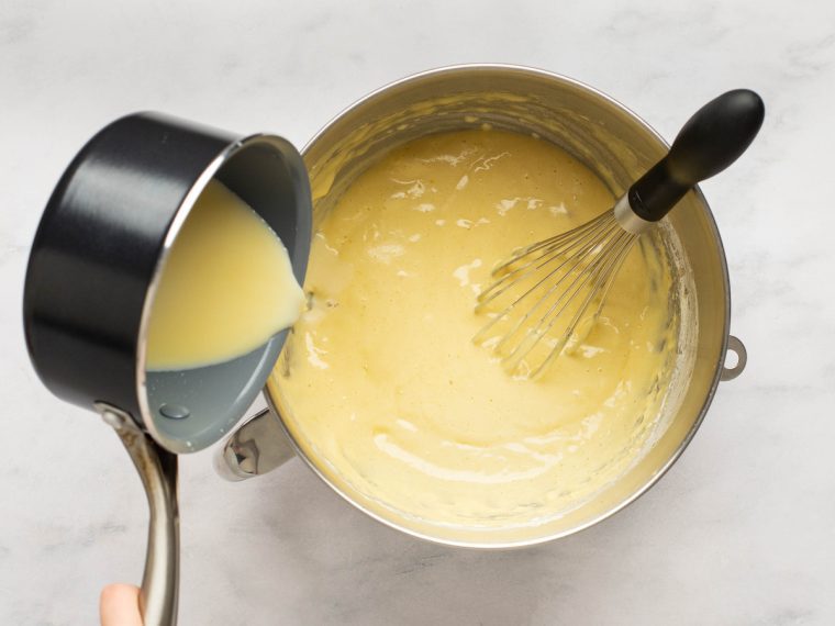 pouring hot milk mixture into bowl with batter