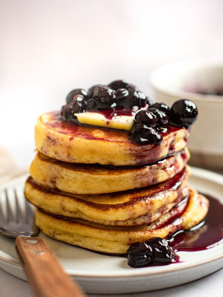Stack of ricotta pancakes on a plate with a fork.