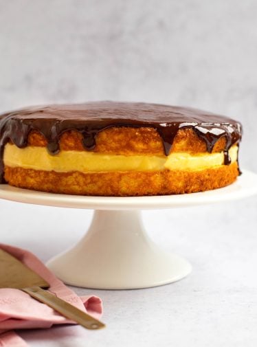 Boston cream pie on a raised serving platter.