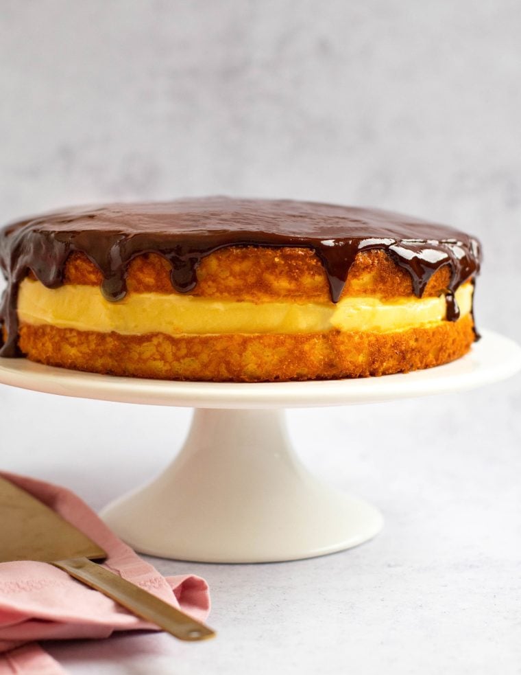 Boston cream pie on a raised serving platter.