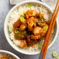 Chopsticks on a bowl of bourbon chicken over rice.