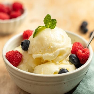 Spoon in a bowl of lemon ice and berries.