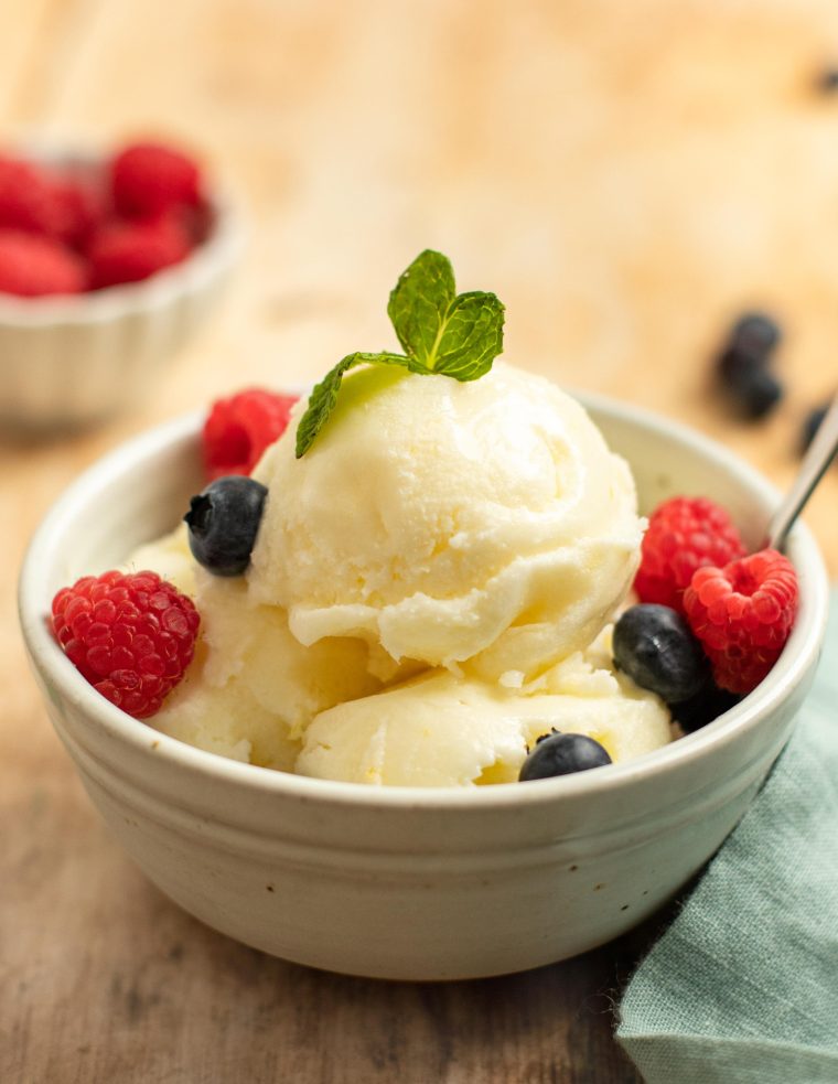 Spoon in a bowl of lemon ice and berries.