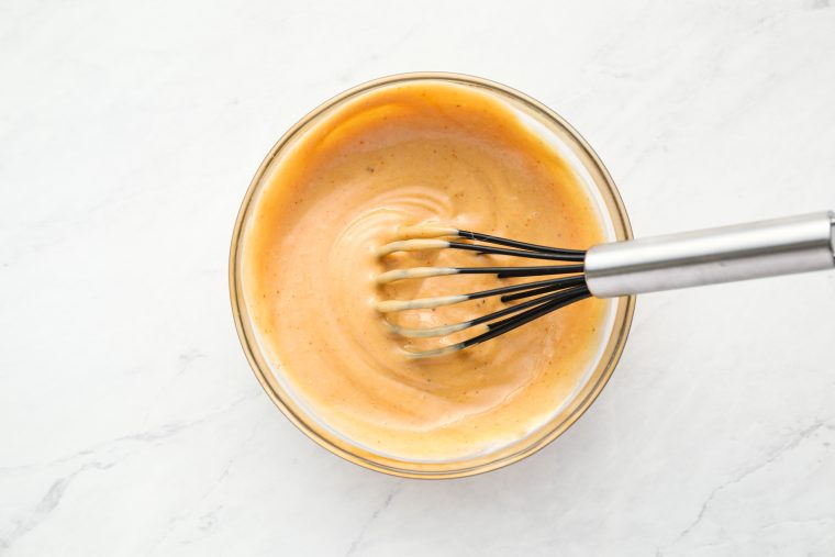 whisking mayonnaise, barbecue sauce, and mustard