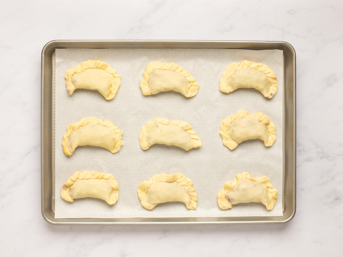 unbaked empanadas on baking sheet