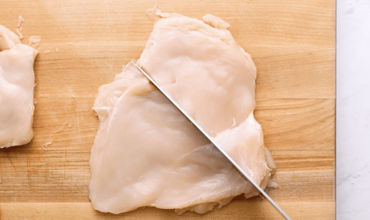 cutting the chicken breasts in half on cutting board