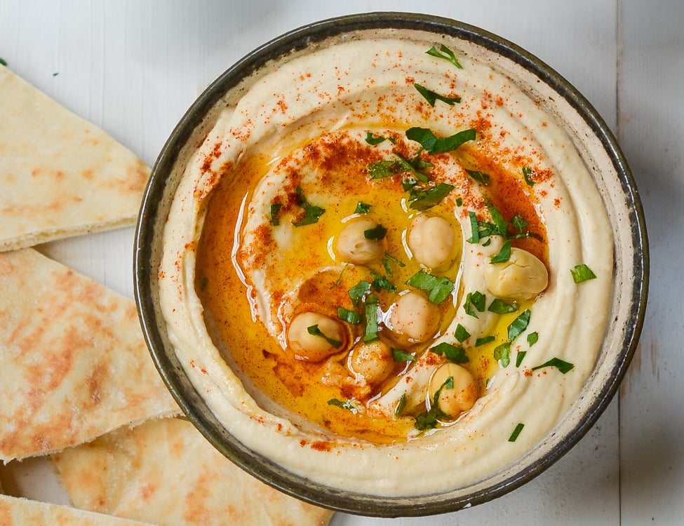 hummus in serving bowl with pita bread