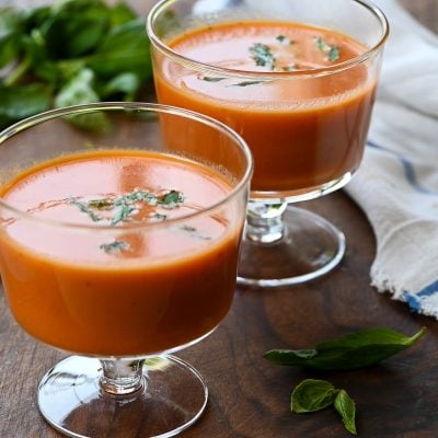 Two stemmed glasses of chilled creamy tomato basil soup.