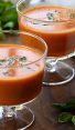 Two stemmed glasses of chilled creamy tomato basil soup.