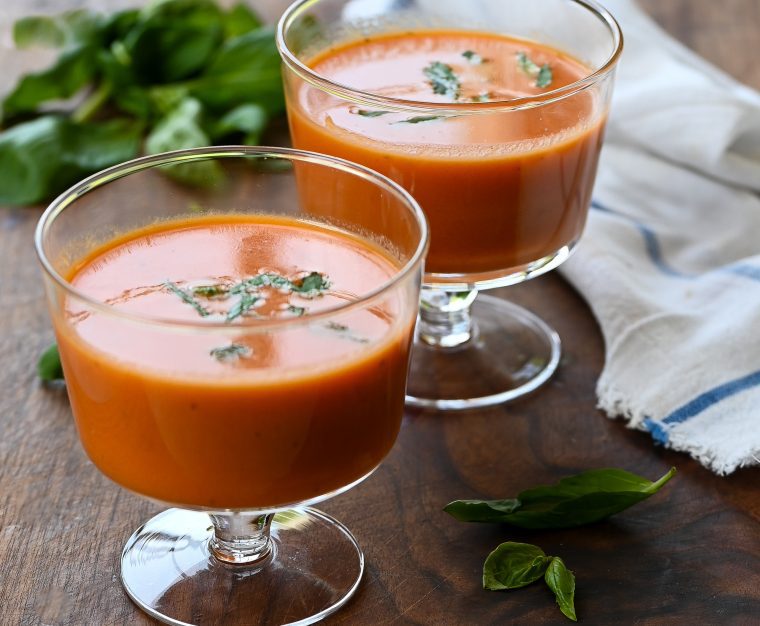 Two stemmed glasses of chilled creamy tomato basil soup.