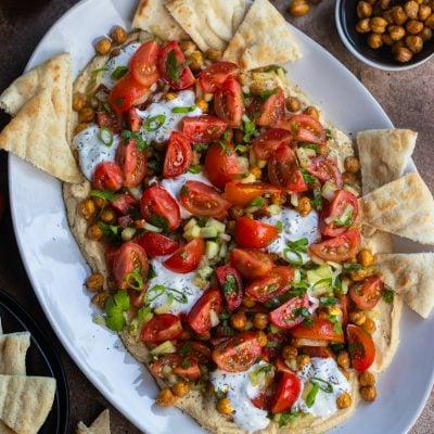 Hummus board with pita, tomatoes, and more.