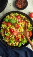 Wooden spoon in a skillet of succotash.