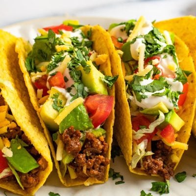 ground beef taco recipe showing stuffed tacos loaded with toppings.