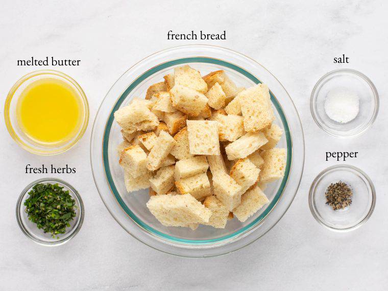 Crouton ingredients, including French bread, fresh herbs, and melted butter.