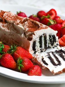 Classic icebox cake with the end cut off, on a plate with strawberries.