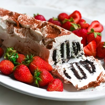 Classic icebox cake with the end cut off, on a plate with strawberries.