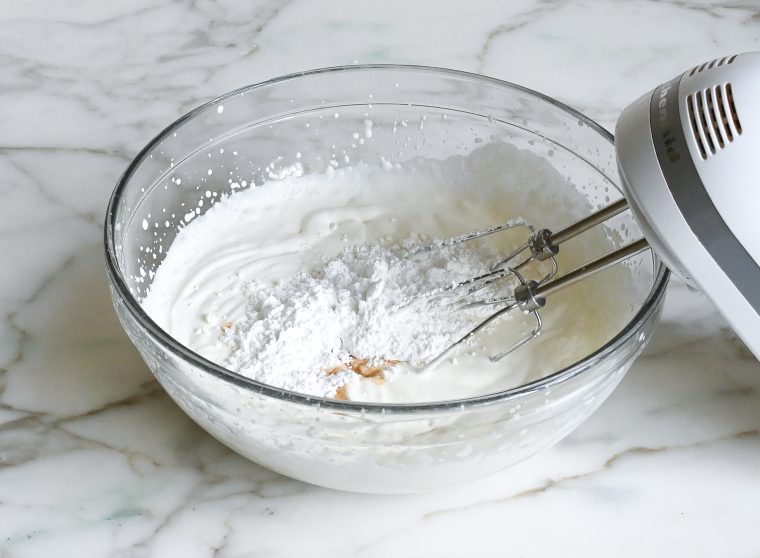 adding the sugar, vanilla, and salt to the softly whipped cream