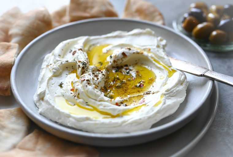 Labneh on serving plate with olives and pita.