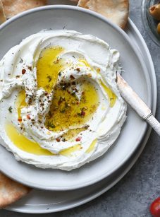 labneh on plate with olive oil, tomatoes and olives on the side