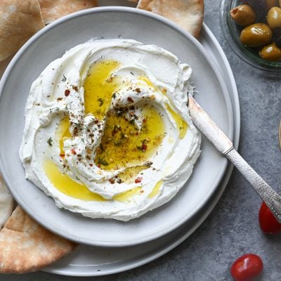 labneh on plate with olive oil, tomatoes and olives on the side