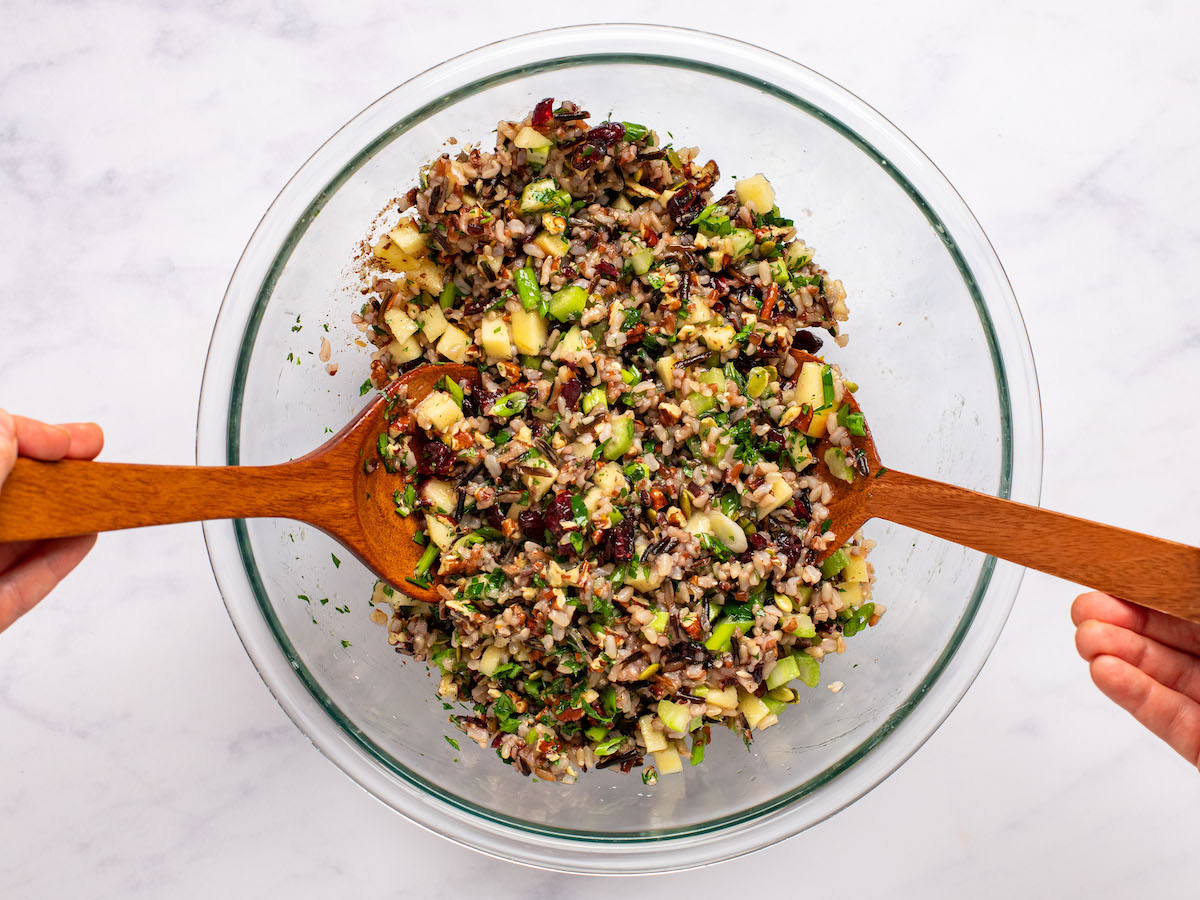tossing rice with dried cranberries, parsley, celery, apples, pepitas, and scallions