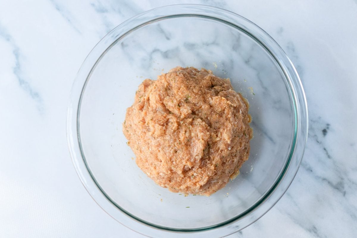 Meatball ingredients mixed in a glass bowl.