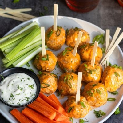 Buffalo chicken meatball on a plate with carrots, celery, and dip.