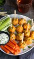 Buffalo chicken meatball on a plate with carrots, celery, and dip.