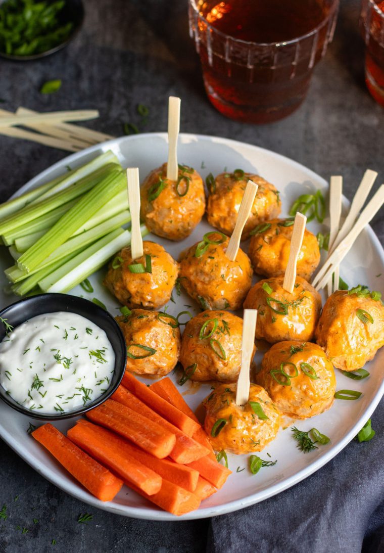 Buffalo chicken meatball on a plate with carrots, celery, and dip.