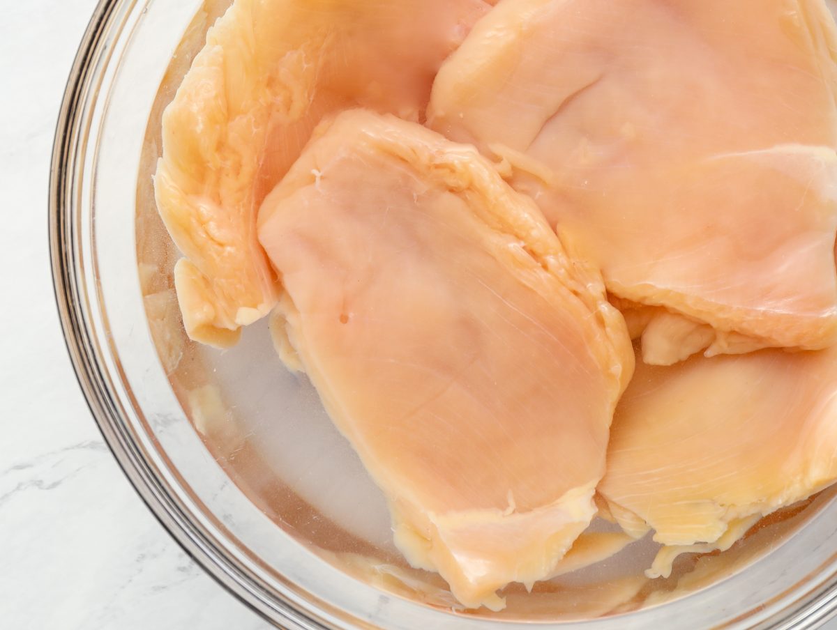 Chicken breasts in a bowl of brine.
