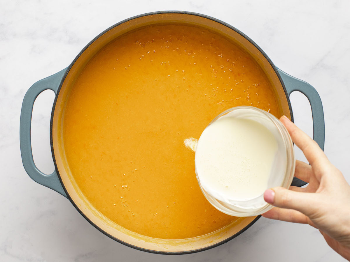 Heavy cream pouring into a pot of soup.