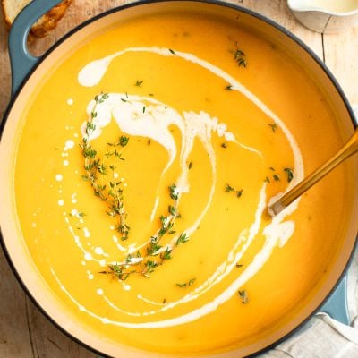 butternut squash soup in Dutch oven drizzled with cream and sprinkled with thyme
