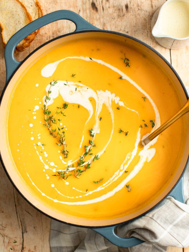 butternut squash soup in Dutch oven drizzled with cream and sprinkled with thyme