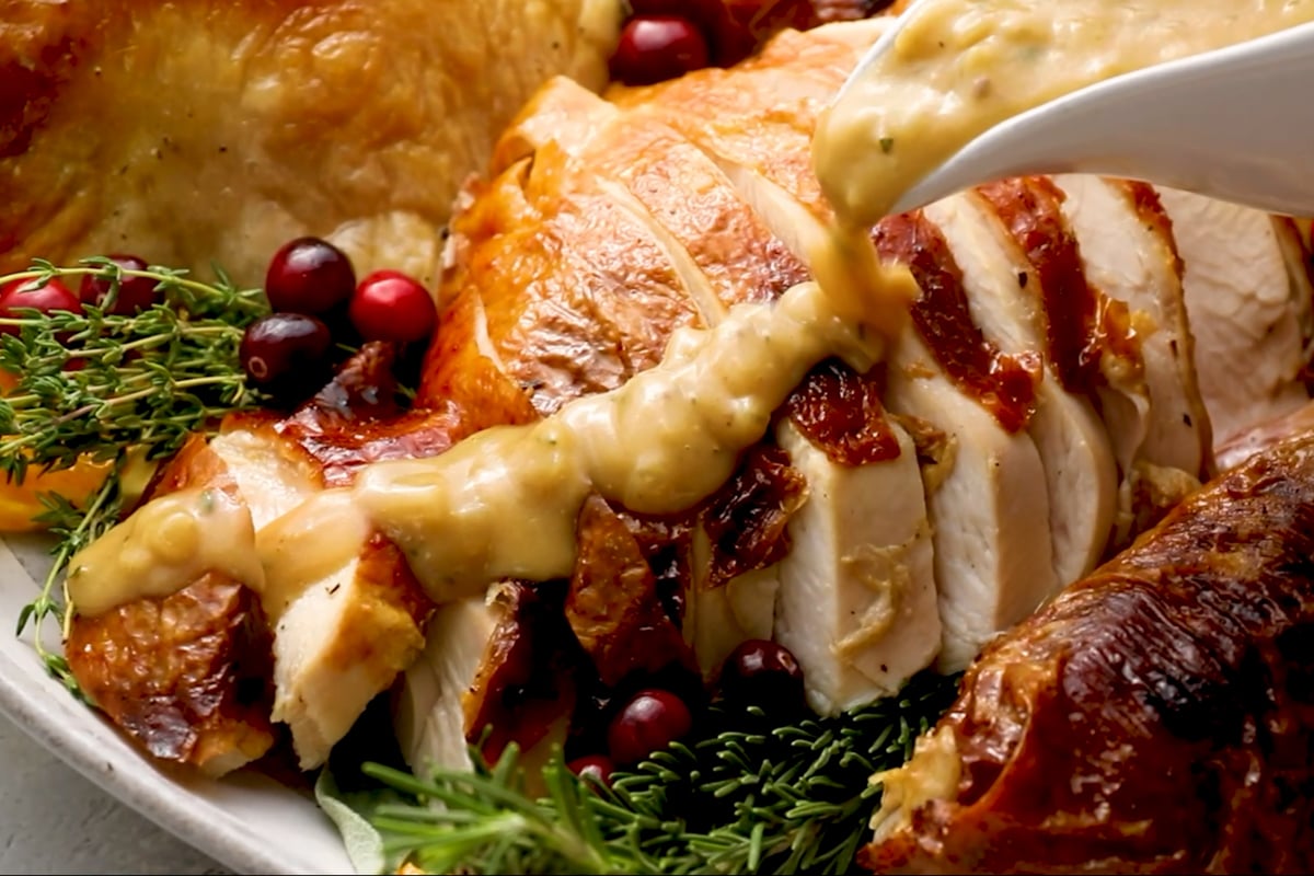 pouring turkey gravy over sliced turkey