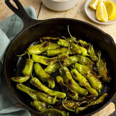 blistered shishito peppers in skillet.