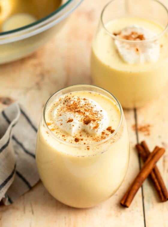 glasses of eggnog with cinnamon sticks.