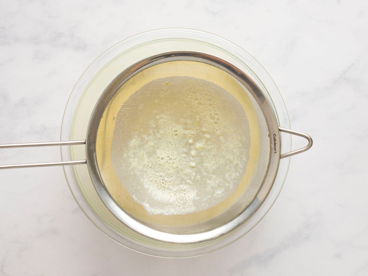 eggnog mixture poured through mesh strainer into large bowl