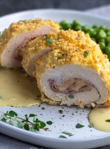 chicken cordon bleu with sauce and peas on plate