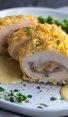 chicken cordon bleu with sauce and peas on plate