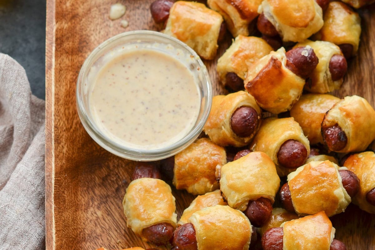 pigs in a blanket on platter with mustard sauce