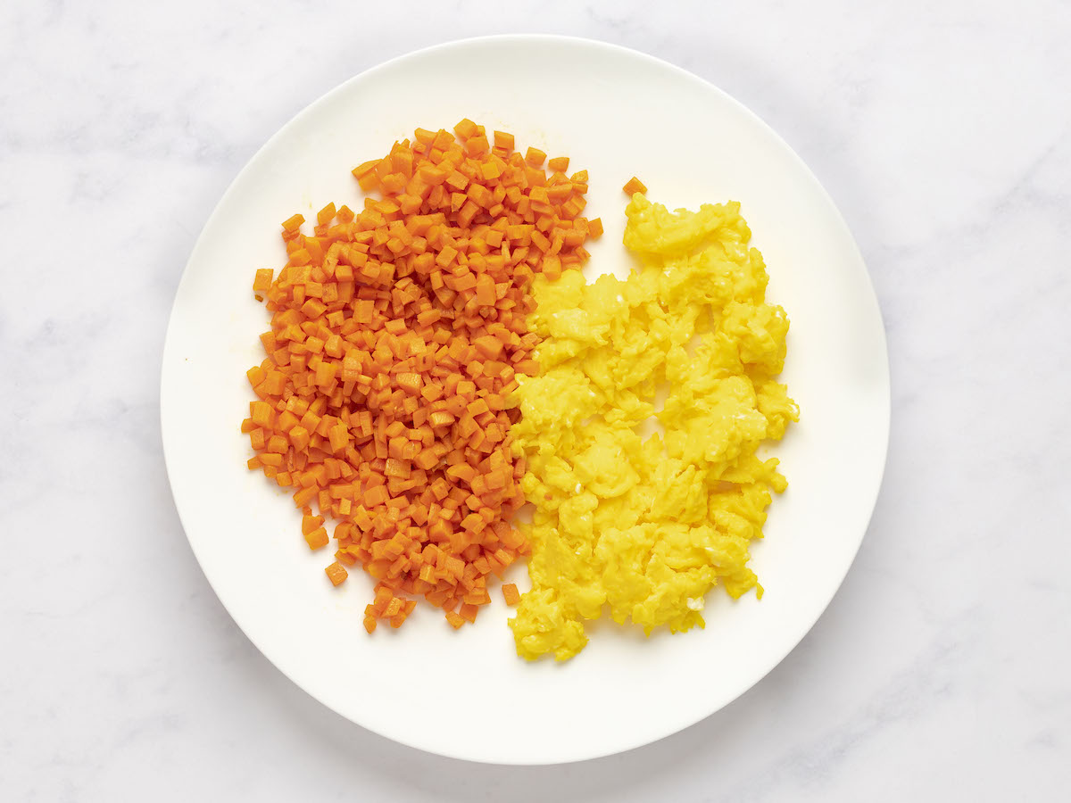 scrambled eggs and cooked carrots side by side on a plate.