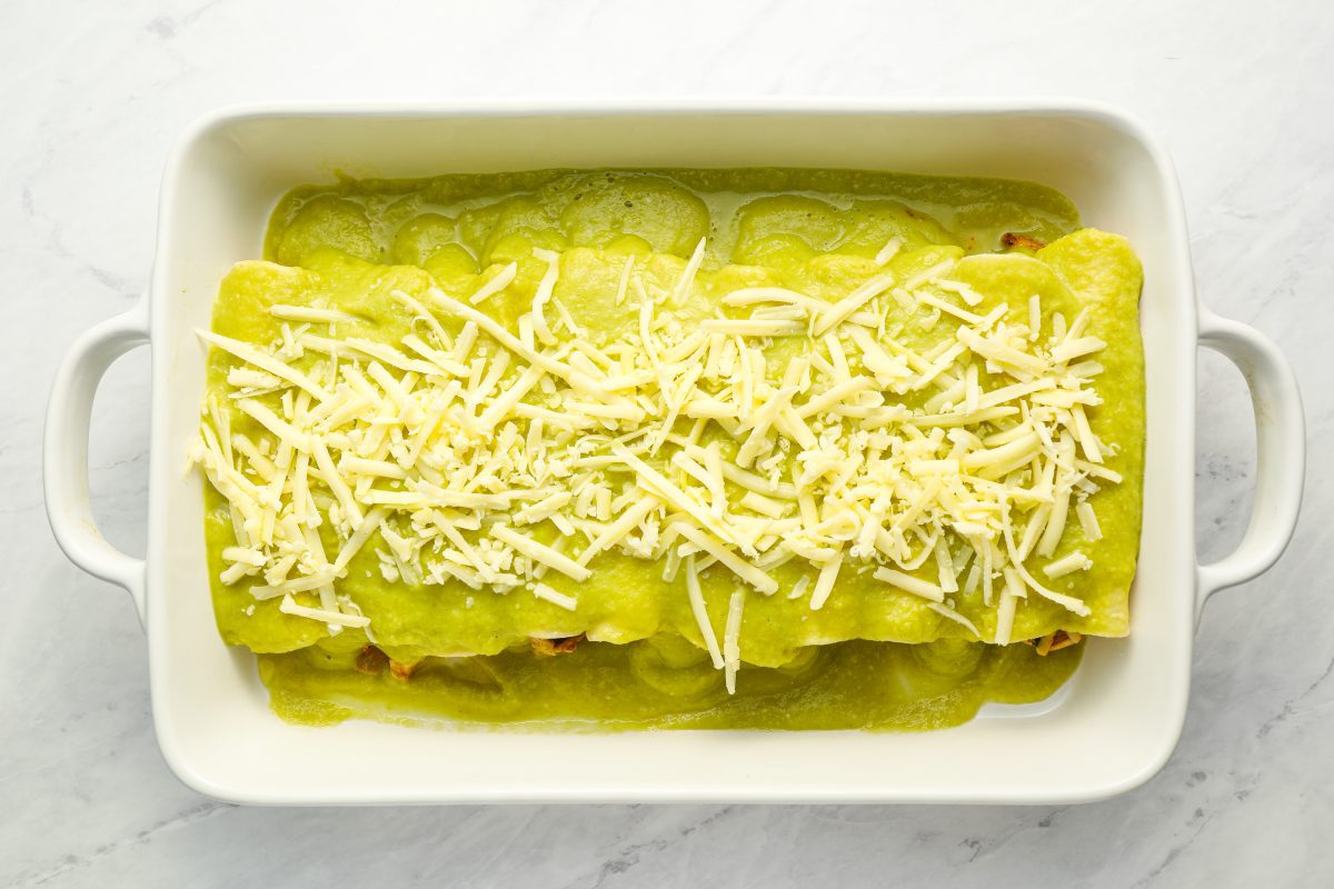 enchiladas covered with sauce and cheese in baking dish.