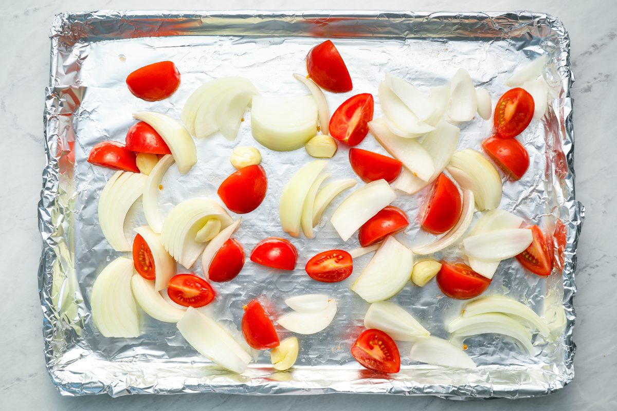 tomatoes, onions, and garlic on baking sheet.