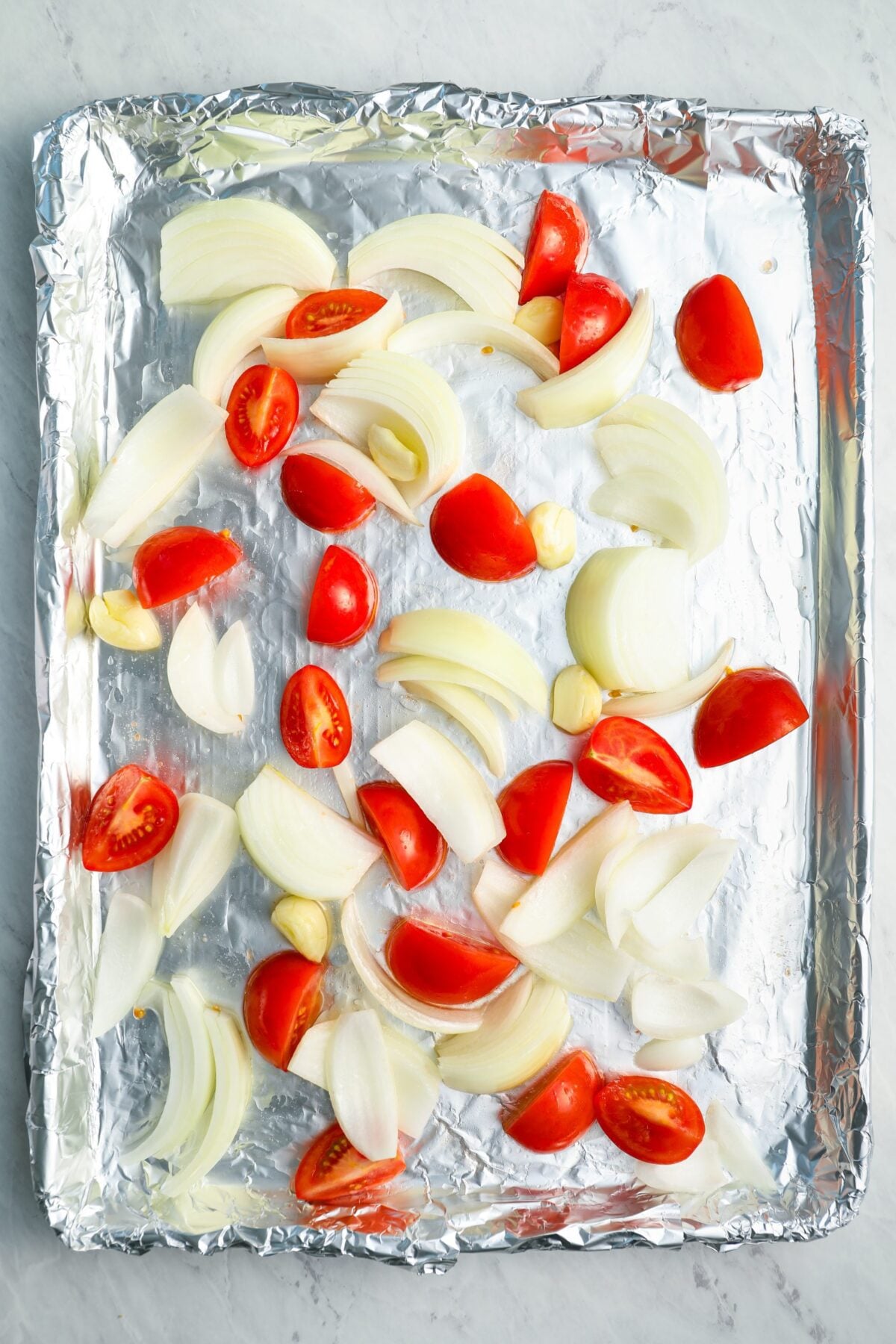tomatoes, onions, and garlic on baking sheet.