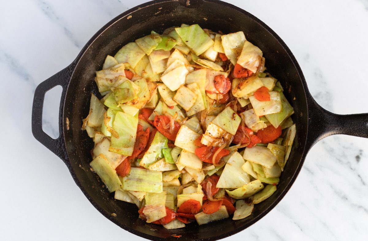 cabbage added to veggies in cast iron skillet