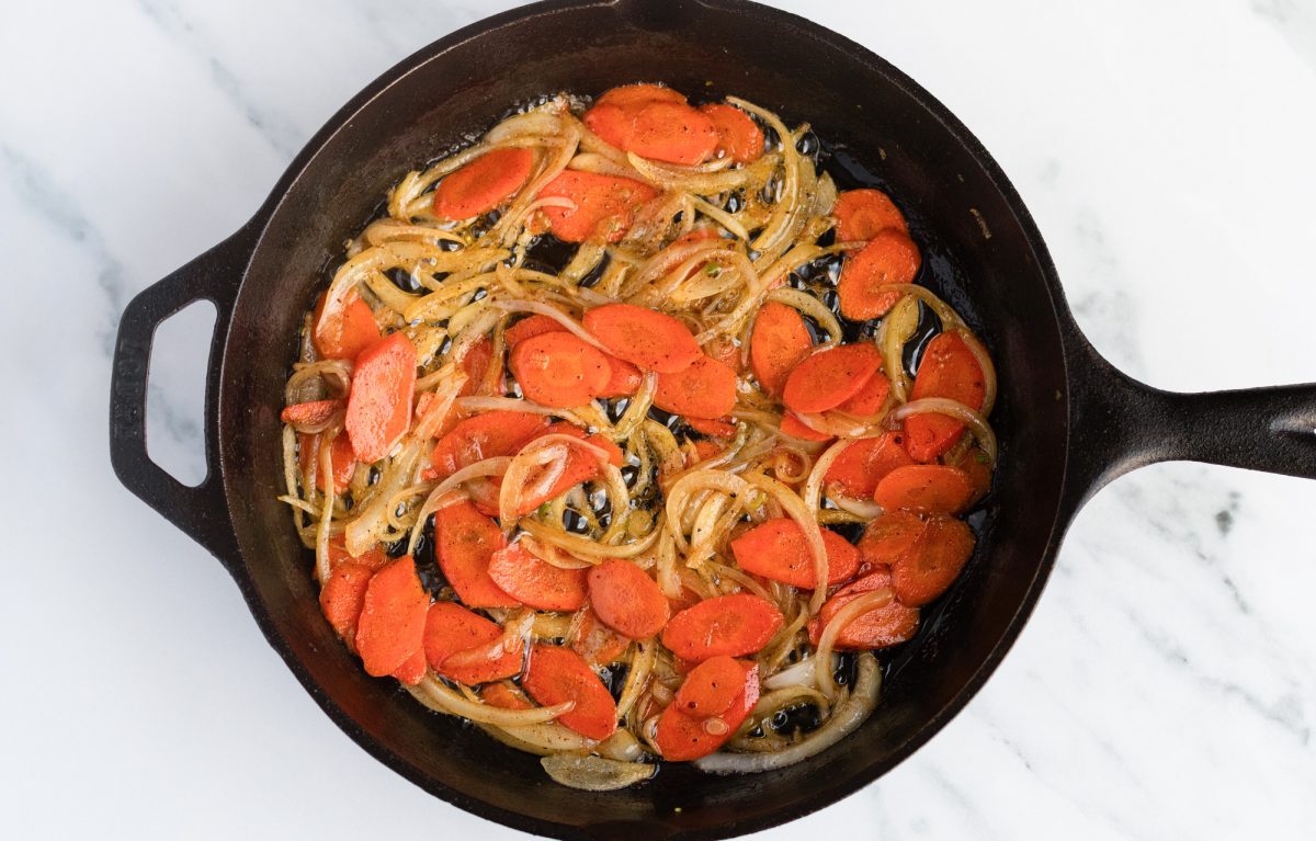 cooked carrots, onions, and scallions in cast iron skillet
